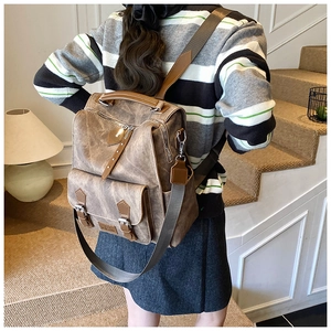 Rear view of a vintage brown leather backpack worn by a model in a cozy indoor setting