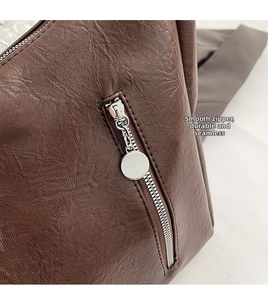 Detail of a smooth silver zipper on a dark brown litchi pattern leather tote bag