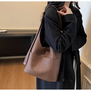 Détail du sac cabas en cuir tressé marron foncé avec poche latérale et boucle dorée