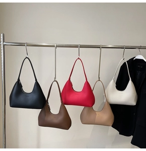 Detailed row of crescent hobo bags in five colors hanging on hooks with litchi grain texture