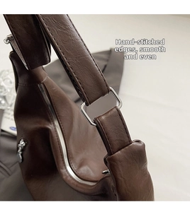 Detail of dark brown litchi pattern leather bag with hand-stitched edging and silver buckle