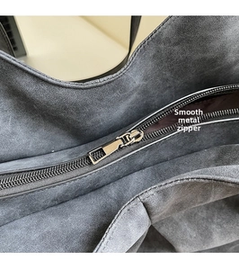 Detail of smooth metal zipper pull and texture of the large grey suede tote bag