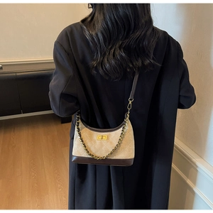 Detail of beige quilted shoulder bag with chain strap and gold twist lock on black blazer