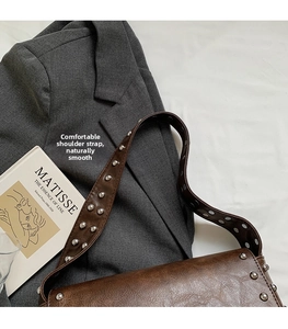 Détail de la large bandoulière rivetée et texture vintage sur le sac en cuir synthétique brun