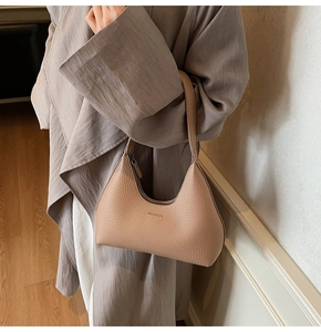 Detailed macro view of the beige hobo bag showing its pebbled leather texture and logo