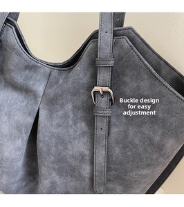Detail of adjustable silver buckle and textured matte finish on large grey tote bag