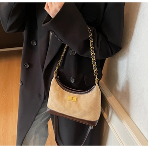 Detail of suede and leather shoulder bag with quilted pattern and gold chain strap