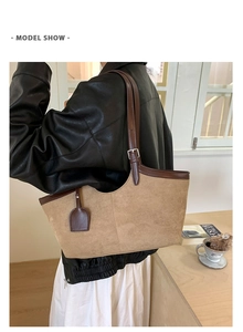 Khaki suede tote bag with brown leather trim shown on model in a cozy indoor setting
