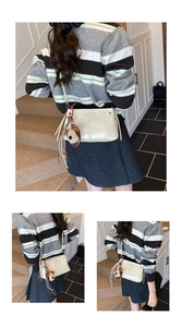 Detail van beige crossbodytas met verticale stiksels en schattige puppy pluche hanger