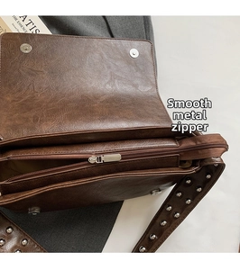 Détail de la fermeture éclair en métal et rivets argentés sur sac en cuir marron