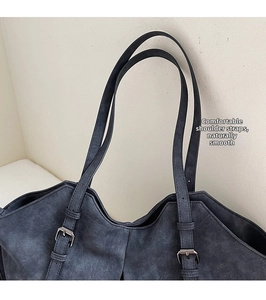 Detail of adjustable shoulder strap and silver metal buckle on a navy matte tote bag