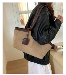 Detail view of a retro camel suede tote bag with dark brown leather straps on shoulder
