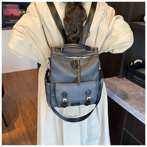 Rear view of black faux leather backpack with double buckle pockets on a beige trench coat