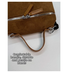 Gros plan du sac en daim marron avec doubles fermetures éclair argentées et anses cuir