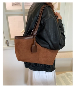 Close-up of vintage brown suede tote bag with dark leather handles on model's shoulder