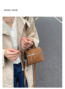 Photo de mode en extérieur du mini sac bandoulière en daim marron avec pendentif