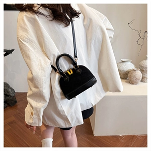 Détail d'un sac bandoulière noir en daim avec fermetures éclair dorées sur chemise blanche