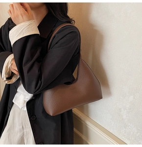 Close-up of dark brown lychee grain leather underarm bag with elegant embossed logo detail