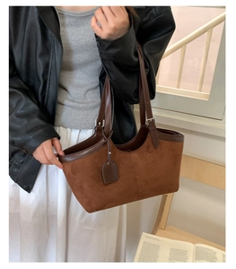 Detail of brown suede tote bag with contrast leather trim and adjustable shoulder strap