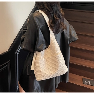 Vue détaillée de la texture tressée crème et de la large bandoulière du sac hobo chic