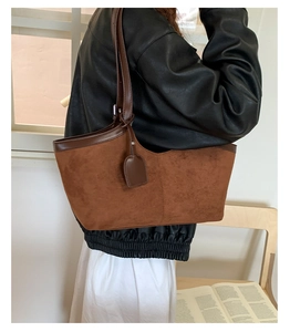 Close-up of brown suede tote bag with leather trim and v-shaped opening detail