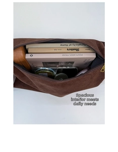 Top view of spacious brown suede bag interior showing books, phone and daily essentials