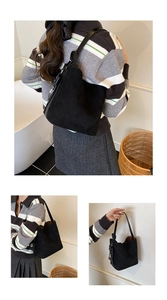 Detail of a large black frosted leather bucket bag featuring a smooth adjustable strap