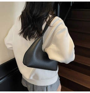 Chic black lychee grain leather hobo shoulder bag styled on a model in a minimalist setting