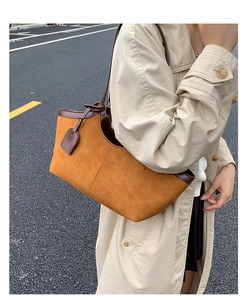 Detail of caramel suede and dark brown leather tote bag worn on shoulder in street style