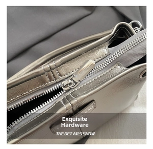 Detail van de zilveren metalen rits en hardware met BAG-gravure op de schoudertas