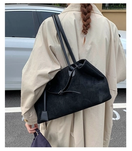Dettaglio di una borsa tote in pelle nera opaca con un ciondolo quadrato in pelle