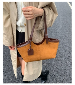 Macro shot of ginger suede tote bag with brown leather handles and silver buckle detail