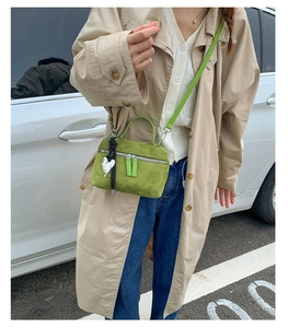 Détail du mini sac bandoulière en daim vert herbe avec breloque cœur et double zip