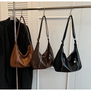 Detail of three retro hobo bags in caramel, brown, and black with metallic pendants