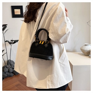 Détail du sac à main matelassé noir avec finitions dorées porté par un mannequin