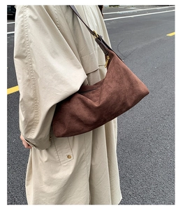 Brown faux suede hobo bag styled with a beige trench coat for a vintage aesthetic