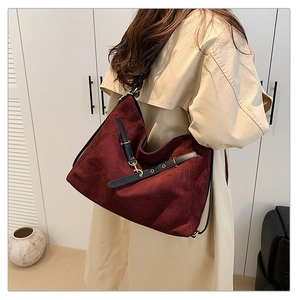 Detalle del bolso tote grande granate con textura de ante y correa de cuero negro