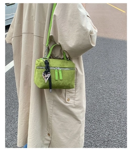 Détail du sac bandoulière en daim vert avec breloque cœur léopard sur manteau beige