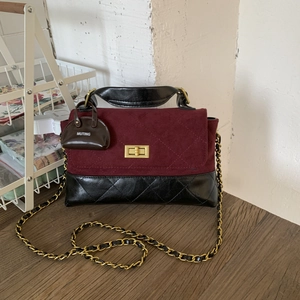 Detail view of burgundy suede and black quilted leather handbag with gold twist-lock closure