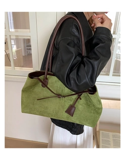 Vista laterale della grande borsa tote in pelle scamosciata verde indossata dalla modella