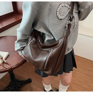 Détail du sac hobo en cuir marron foncé avec doubles fermetures éclair et texture grainée