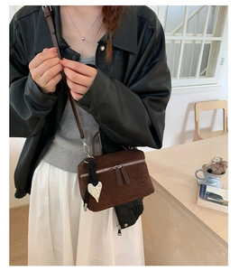 Détail du sac bandoulière en daim marron café avec pendentif cœur et fine bandoulière