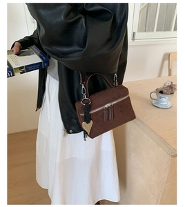 Détail d'un mini sac bandoulière en daim marron avec zip argenté et breloque coeur