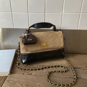 Detail view of quilted dual-tone crossbody bag with gold lock and mini charm accessory