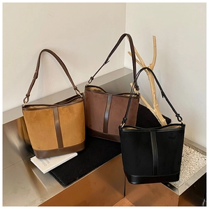 Detailed close-up of retro bucket bags in three colors on a textured metal stand