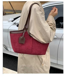 Detail of vintage burgundy suede tote bag with brown leather trim worn over the shoulder