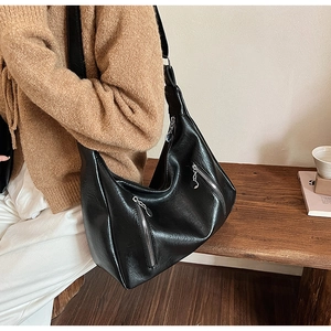 Detail shot of black faux leather hobo bag with dual metal zippers and wide shoulder strap