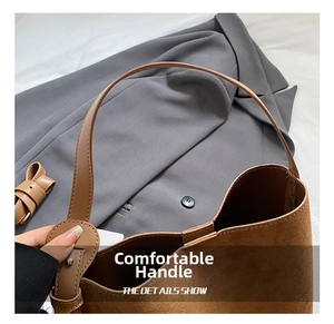 Detail of matte brown suede shoulder bag with wide leather strap and silver ring buckle