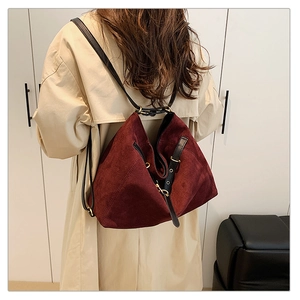 Detalle del bolso de ante burdeos con correas negras ajustables y herrajes dorados