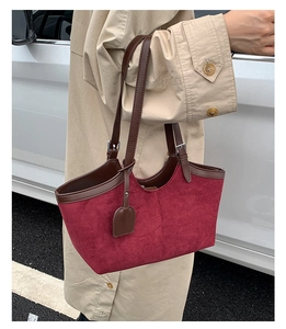 Detail of burgundy suede tote bag with brown leather handles and metal buckle adjustments